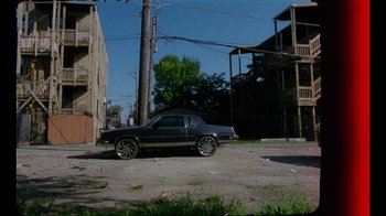 Movie still from “Pass Over” (2018), directed by Danya Taymor – A black car parked on the side of the road; Extreme Wide shot, High angle