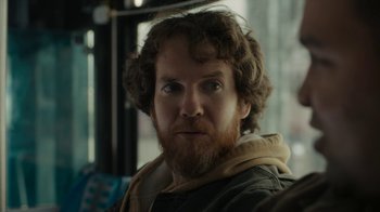 Movie still from “Paterson” (2016), directed by Jim Jarmusch – A person with a beard on a bus; Close Up shot, Over the shoulder angle