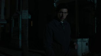 Movie still from “Paterson” (2016), directed by Jim Jarmusch – A man standing in the dark in a dark room; Medium shot, High angle