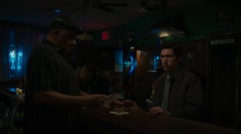 Movie still from “Paterson” (2016), directed by Jim Jarmusch – A man sitting at a counter with a man holding a card; Medium shot, Over the shoulder angle