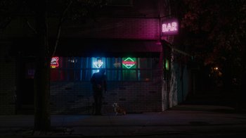 Movie still from “Paterson” (2016), directed by Jim Jarmusch – A man and a dog in front of a bar at night; Extreme Wide shot, Over the shoulder angle