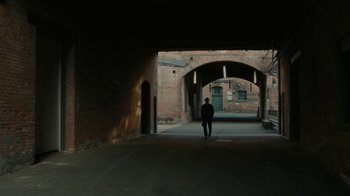 Movie still from “Paterson” (2016), directed by Jim Jarmusch – A man walking down a street under an archway; Extreme Wide shot, Low angle