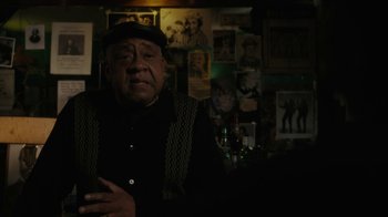 Movie still from “Paterson” (2016), directed by Jim Jarmusch – An older man is standing in front of a wall; Medium shot, Over the shoulder angle