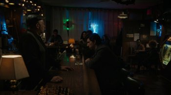 Movie still from “Paterson” (2016), directed by Jim Jarmusch – A group of people sitting at a table in a room; Wide shot, Over the shoulder angle