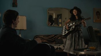 Movie still from “Paterson” (2016), directed by Jim Jarmusch – A woman holding a guitar in a living room; Medium shot, Over the shoulder angle