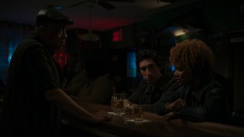 Movie still from “Paterson” (2016), directed by Jim Jarmusch – A group of people sitting at a table with drinks on it; Medium shot, Over the shoulder angle