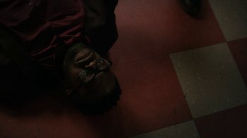 Movie still from “Paterson” (2016), directed by Jim Jarmusch – A man laying on the ground with his head down; Close Up shot, Overhead angle