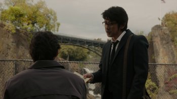 Movie still from “Paterson” (2016), directed by Jim Jarmusch – A man wearing a suit and tie talking to another man wearing a jacket; Medium shot, Over the shoulder angle