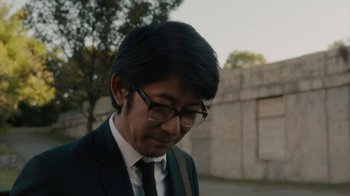 Movie still from “Paterson” (2016), directed by Jim Jarmusch – A person wearing a suit and glasses; Close Up shot, Low angle