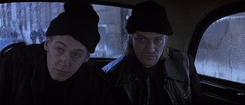 Movie still from “Patriot Games” (1992), directed by Phillip Noyce – Two people in a car looking at the camera; Close Up shot, Low angle