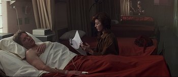 Movie still from “Patriot Games” (1992), directed by Phillip Noyce – A woman sitting on a bed holding a paper; Medium shot, Over the shoulder angle