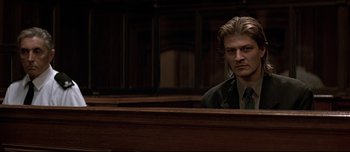 Movie still from “Patriot Games” (1992), directed by Phillip Noyce – A man sitting in front of a judge's bench; Close Up shot, Low angle