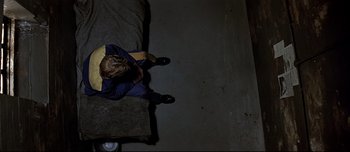 Movie still from “Patriot Games” (1992), directed by Phillip Noyce – A person sitting on a couch in a dark room; Wide shot, Overhead angle