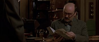 Movie still from “Patriot Games” (1992), directed by Phillip Noyce – A man sitting at a table reading a book; Close Up shot, Low angle