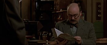 Movie still from “Patriot Games” (1992), directed by Phillip Noyce – An older man sitting at a table reading a book; Close Up shot, Low angle
