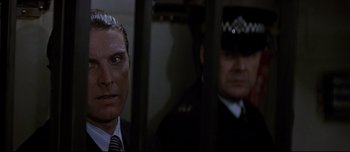 Movie still from “Patriot Games” (1992), directed by Phillip Noyce – A man in a suit and tie standing next to another man in a uniform; Close Up shot, Low angle