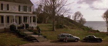 Movie still from “Patriot Games” (1992), directed by Phillip Noyce – Two people standing on the steps of a house next to a parked car; Extreme Wide shot, High angle