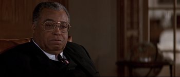 Movie still from “Patriot Games” (1992), directed by Phillip Noyce – An older man wearing glasses and a suit; Close Up shot, Over the shoulder angle