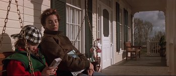 Movie still from “Patriot Games” (1992), directed by Phillip Noyce – A woman sitting on a porch holding a cell phone; Medium shot, Low angle