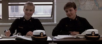Movie still from “Patriot Games” (1992), directed by Phillip Noyce – Two people sitting at a table with a hat on top; Medium shot, Over the shoulder angle