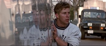 Movie still from “Patriot Games” (1992), directed by Phillip Noyce – A man leaning against a wall with his hand on his face; Medium shot, Low angle