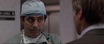 Movie still from “Patriot Games” (1992), directed by Phillip Noyce – A man wearing a surgical cap and a surgical gown; Close Up shot, Over the shoulder angle