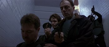 Movie still from “Patriot Games” (1992), directed by Phillip Noyce – A group of people holding guns in a room; Medium shot, Low angle