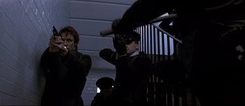 Movie still from “Patriot Games” (1992), directed by Phillip Noyce – A man holding a baseball bat while standing next to a staircase; Medium shot, Low angle