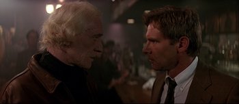 Movie still from “Patriot Games” (1992), directed by Phillip Noyce – A man and an old man face each other in front of a crowd; Close Up shot, Over the shoulder angle