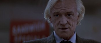 Movie still from “Patriot Games” (1992), directed by Phillip Noyce – An older man with white blonde hair and blue eyes wearing a suit; Close Up shot, Low angle