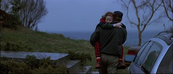 Movie still from “Patriot Games” (1992), directed by Phillip Noyce – A man holding a little girl in his arms; Medium shot, Over the shoulder angle