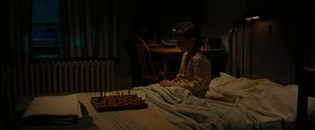 Movie still from “Pawn Sacrifice” (2014), directed by Edward Zwick – A woman sitting on a bed playing a game of chess; Medium shot, High angle