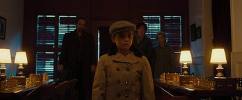 Movie still from “Pawn Sacrifice” (2014), directed by Edward Zwick – A young boy in a coat and hat stands in front of a group of people; Medium shot, Over the shoulder angle