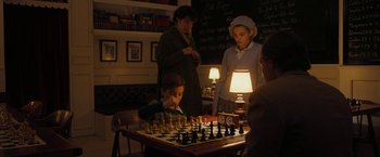 Movie still from “Pawn Sacrifice” (2014), directed by Edward Zwick – A group of people standing around a table with a chess set; Medium shot, High angle