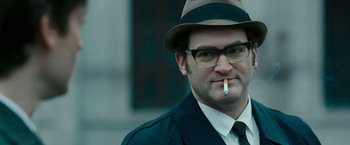 Movie still from “Pawn Sacrifice” (2014), directed by Edward Zwick – A person wearing a hat and smoking a cigarette; Close Up shot, Over the shoulder angle