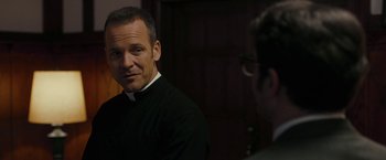 Movie still from “Pawn Sacrifice” (2014), directed by Edward Zwick – A man wearing a priest's outfit and glasses is talking to another man; Close Up shot, Over the shoulder angle