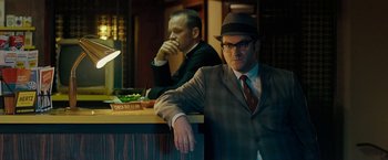 Movie still from “Pawn Sacrifice” (2014), directed by Edward Zwick – A man sitting at a counter next to another man wearing a hat; Medium shot, Over the shoulder angle