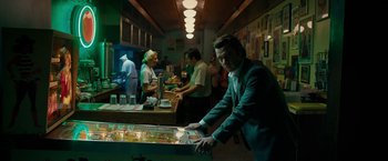 Movie still from “Pawn Sacrifice” (2014), directed by Edward Zwick – A group of people standing in a room with a pinball machine; Medium shot, Low angle