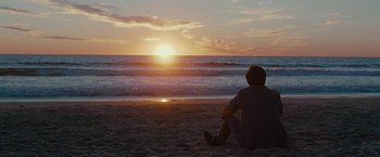 Movie still from “Pawn Sacrifice” (2014), directed by Edward Zwick – A man sitting on the beach watching the sun go down over the ocean; Wide shot, Low angle