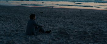 Movie still from “Pawn Sacrifice” (2014), directed by Edward Zwick – A man sitting on the beach at night; Wide shot, High angle
