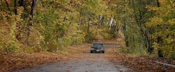 Movie still from “Pawn Sacrifice” (2014), directed by Edward Zwick – A car driving down a road surrounded by fall leaves; Extreme Wide shot, High angle