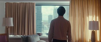 Movie still from “Pawn Sacrifice” (2014), directed by Edward Zwick – A man standing in front of a window looking out at a city; Medium shot, Over the shoulder angle