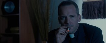 Movie still from “Pawn Sacrifice” (2014), directed by Edward Zwick – A man in a priest's outfit smoking a cigarette; Close Up shot, Over the shoulder angle