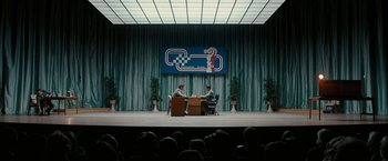 Movie still from “Pawn Sacrifice” (2014), directed by Edward Zwick – Two men are sitting at a table in front of an audience; Extreme Wide shot, Over the shoulder angle