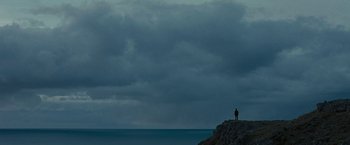 Movie still from “Pawn Sacrifice” (2014), directed by Edward Zwick – A person standing on a rock near the ocean; Extreme Wide shot, Low angle