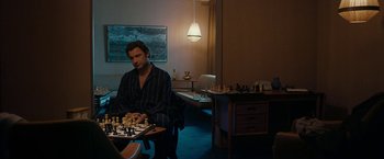 Movie still from “Pawn Sacrifice” (2014), directed by Edward Zwick – A man sitting in front of a chess board in a living room; Medium shot, High angle