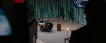 Movie still from “Pawn Sacrifice” (2014), directed by Edward Zwick – Two men sitting at a table in front of each other in front of green curtains; Extreme Wide shot, High angle