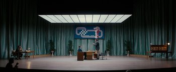 Movie still from “Pawn Sacrifice” (2014), directed by Edward Zwick – Two people sitting at a table in front of a checkerboard backdrop; Extreme Wide shot, High angle