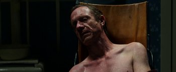 Movie still from “Pearl” (2022), directed by Ti West – A shirtless man sitting in a chair with his eyes wide open; Close Up shot, Low angle