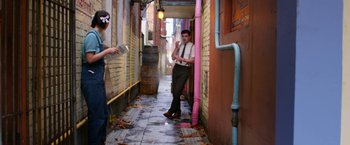 Movie still from “Pearl” (2022), directed by Ti West – A man standing in an alleyway next to a building; Wide shot, Over the shoulder angle